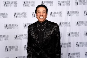 Smokey Robinson smiling in formal attire at a red carpet event.