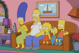 The Simpson family sitting together on a couch in their living room.