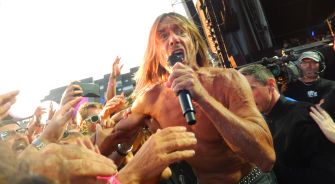 Iggy Pop performing energetically on stage at Coachella, engaging with the audience.