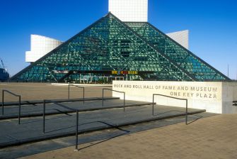 Image of the Rock & Roll Hall of Fame and Museum, featuring its distinctive glass pyramid structure and entrance plaza.