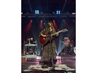Ella Langley performing live at the Stagecoach Festival on a well-lit stage, playing guitar and engaging with the audience.