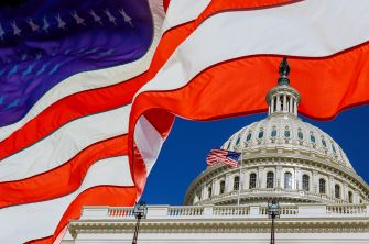The U.S. Capitol building partially obscured by an American flag, symbolizing the upcoming 250th birthday celebration of the United States.