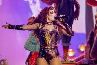 Chappell Roan performing on stage, wearing a unique costume and holding a microphone.