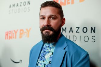 Shia LaBeouf at a film event, wearing a blue suit and patterned shirt.