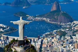 Aerial view of Rio de Janeiro, featuring the Christ the Redeemer statue and surrounding mountains and coastline.