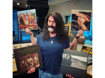 Pierre Robert holding vinyl records in a radio studio setting.