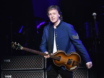 Paul McCartney performing on stage with his bass guitar.