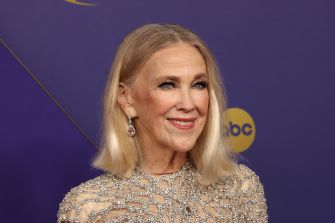 Catherine O'Hara smiling at an event, wearing a beaded dress and earrings.