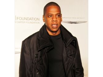 Jay-Z posing in a black coat at an event.