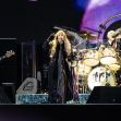 Fleetwood Mac performing live on stage, with band members playing instruments and singing. Fleetwood Mac performing live on stage, with band members playing instruments and singing.