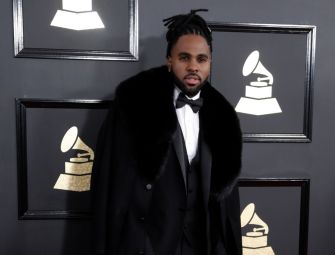 Pop singer Jason Derulo at a formal event, wearing a black tuxedo with a fur-collared coat.