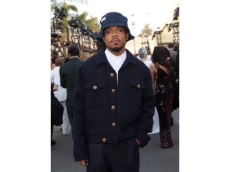 Chance the Rapper attending an event, dressed in a dark jacket and bucket hat.