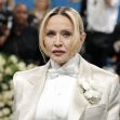 Madonna wearing a formal outfit at an event, surrounded by a floral backdrop and an audience. Madonna wearing a formal outfit at an event, surrounded by a floral backdrop and an audience.
