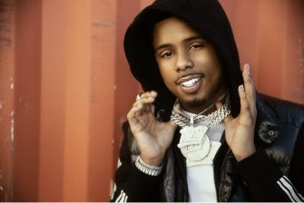Portrait of Memphis rapper Pooh Shiesty, wearing a black hooded jacket and showing off jewelry.