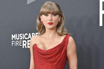 Taylor Swift at a red carpet event, wearing a stunning red dress with elegant accessories.