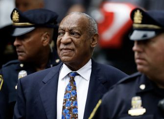 Bill Cosby surrounded by police officers during a court appearance.