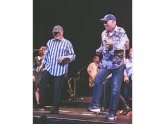 Bruce Johnston and Mike Love performing on stage during a concert.