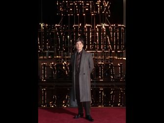 Cillian Murphy posing at a premiere event with a Netflix sign in the background.