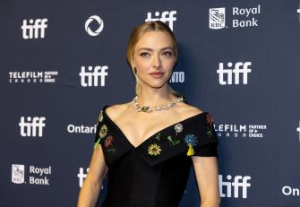 Amanda Seyfried at a red carpet event, wearing a black dress with floral embellishments.