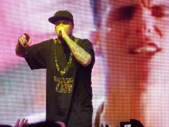 Vanilla Ice performing on stage with a colorful backdrop.