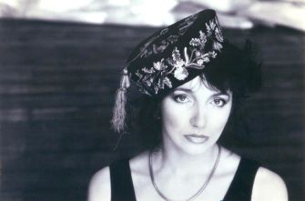 Black-and-white portrait of a woman wearing an embroidered hat, set against a blurred background.