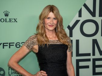 Laura Dern posing at an event, wearing a black dress with embellished details.