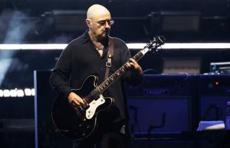 Paul Arthurs playing guitar on stage during a performance.