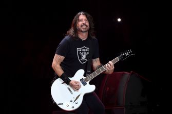 Dave Grohl performing on stage with a white guitar.