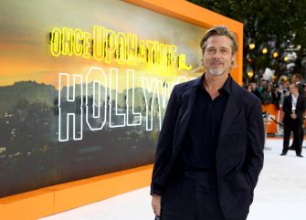 Brad Pitt poses at a promotional event for 'Once Upon a Time in Hollywood,' with a backdrop featuring the film's title.