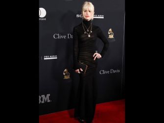 A person in a stylish black dress poses on the red carpet at a formal event.