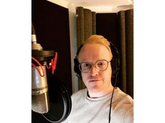 A self-portrait of Owain Rhys Davies in a recording studio, wearing headphones and glasses.