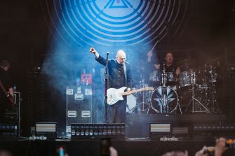 Billy Corgan performing on stage with a guitar, accompanied by a drummer, during a concert.