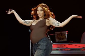 Cardi B performing on stage while visibly pregnant, expressing joy and confidence.