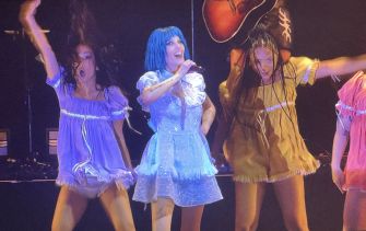 Halsey performing on stage surrounded by dancers, dressed in colorful outfits during her "For My Last Trick" tour concert.