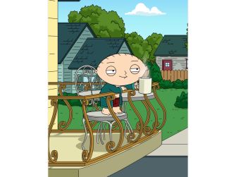 Stewie Griffin sitting on a balcony holding a cup, with a suburban background.