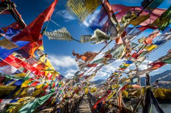 Colorful Tibetan prayer flags fluttering in the wind, creating a vibrant scene against a blue sky.