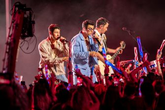 The Jonas Brothers performing live on stage with fans in the foreground, capturing a moment of high energy during their concert.