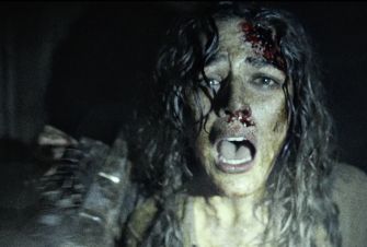 A distressed character with blood on their face, conveying horror and fear in a dark, chaotic environment.