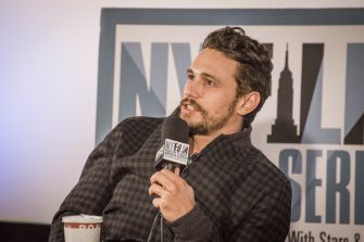 James Franco speaking into a microphone during a discussion event.