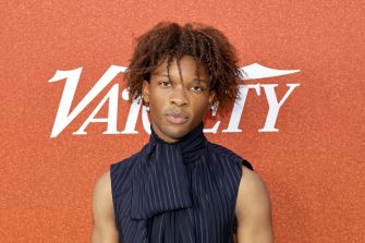 Singer D4vd attending an event, with a focus on his hairstyle and fashion.