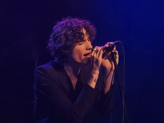 A performer passionately singing into a microphone during a live music set.