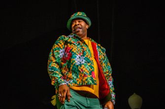 Busta Rhymes performing on stage in a colorful outfit.