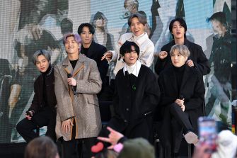 A group of seven individuals poses together in a public setting, showcasing their camaraderie and style during a promotional event.