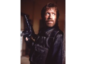 Chuck Norris in a dramatic pose with a weapon, reflecting his iconic action star image.