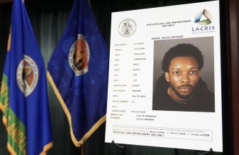 Mugshot of David Anthony Burke displayed on an official law enforcement board, alongside flags in the background.