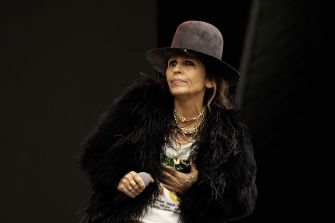 Linda Perry performing on stage, wearing a hat and a black fur jacket.