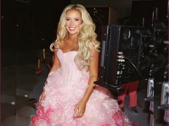 Country singer-songwriter Megan Moroney wearing a pink ball gown and smiling, getting ready for an event.