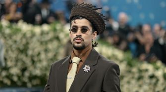 Bad Bunny arrives at an event wearing sunglasses and a unique hat, showcasing his distinct style.