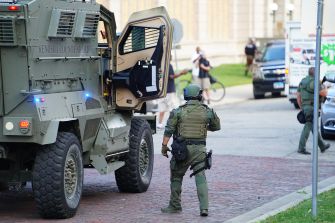 SWAT team members near an armored vehicle during a law enforcement operation.