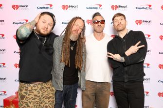 Group of four musicians posing together at an event, with relaxed expressions and casual attire.